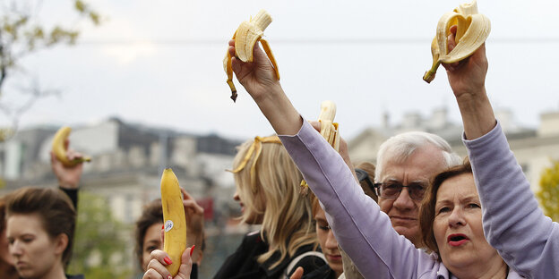 Menschen halten angebissene Bananen hoch