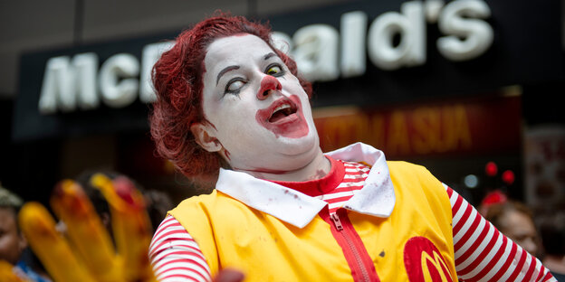 Vor einer McDonalds-Filiale steht ein Mensch, der sich als Zombieversion von Ronald McDonald verkleidet hat Vor einer McDonalds-Filiale steht ein Mensch, der sich als Zombieversion von Ronald McDonald verkleidet hat
