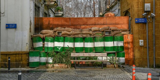Fässer, Säcke und Trennwände, die eine Gasse versperren Fässer, Säcke und Trennwände, die eine Gasse versperren