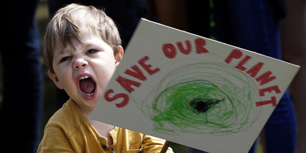 Ein schreiendes Kleinkind hält ein Schild mit den Worten „Save the Planet"“ Ein schreiendes Kleinkind hält ein Schild mit den Worten „Save the Planet"“