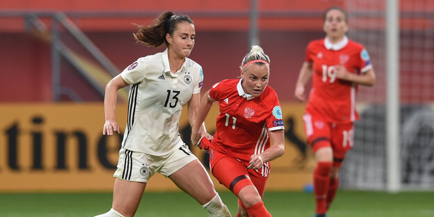 Eine deutsche Fußballerin im weißen Trikot im Zweikampf mit einer russischen Fußballerin im roten Trikot.