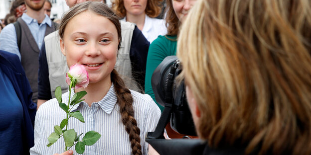 Greta Thunberg hält eine Rose und wird fotografiert Greta Thunberg hält eine Rose und wird fotografiert