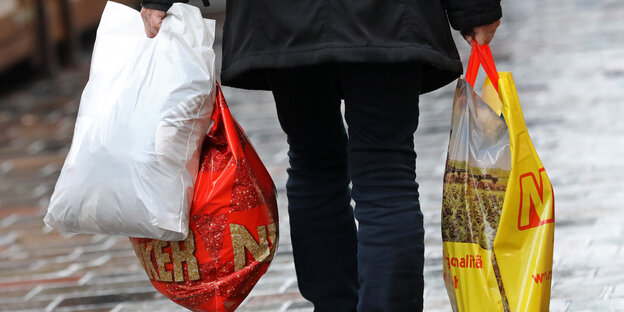 Eine Frau trägt drei Plastiktüten Eine Frau trägt drei Plastiktüten