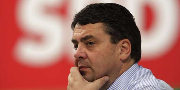 Sigmar Gabriel sitzt vor dem SPD Logo und schaut nachdenklich Sigmar Gabriel sitzt vor dem SPD Logo und schaut nachdenklich