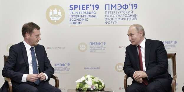 Kretschmer und Putin sitzen auf Stühlen und reden miteinder Kretschmer und Putin sitzen auf Stühlen und reden miteinder