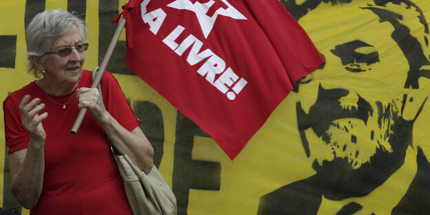 Ein Mensch steht vor einem Transparent und hält eine rote Flagge Ein Mensch steht vor einem Transparent und hält eine rote Flagge