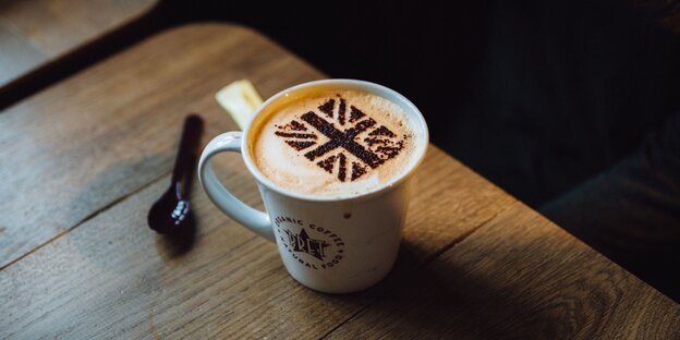 Eine Kaffeetasse mit Milchschaum. Darauf ist mit Kakaopulver die britische Flagge gestreut Eine Kaffeetasse mit Milchschaum. Darauf ist mit Kakaopulver die britische Flagge gestreut