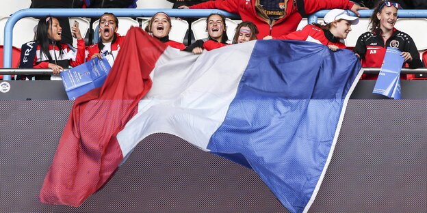 Frauen auf einer Fußball-Tribüne halten die französische Flagge Frauen auf einer Fußball-Tribüne halten die französische Flagge