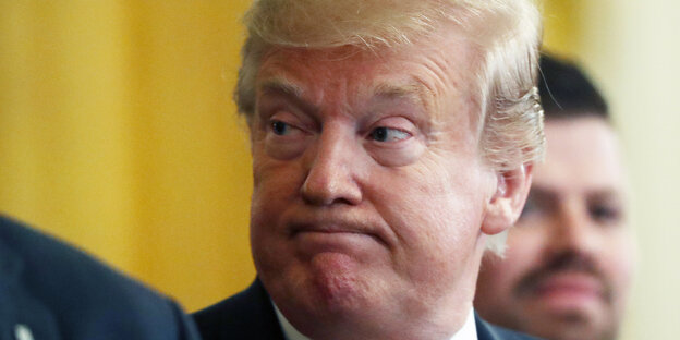 Trump mit zusammengepressten Lippen vor gelbem Hintergrund Trump mit zusammengepressten Lippen vor gelbem Hintergrund