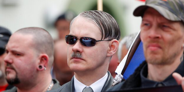 Drei Nazi-Gesichter, das in der Mitte mit Sonnenbrille auf der Nase und Hitlerschnauzbart Drei Nazi-Gesichter, das in der Mitte mit Sonnenbrille auf der Nase und Hitlerschnauzbart