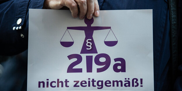 Eine Frau hält bei einer Kundgebung vor Beginn eines Berufungsprozesses einen Zettel mit der Aufschrift «219a nicht zeitgemäß!» Eine Frau hält bei einer Kundgebung vor Beginn eines Berufungsprozesses einen Zettel mit der Aufschrift «219a nicht zeitgemäß!»