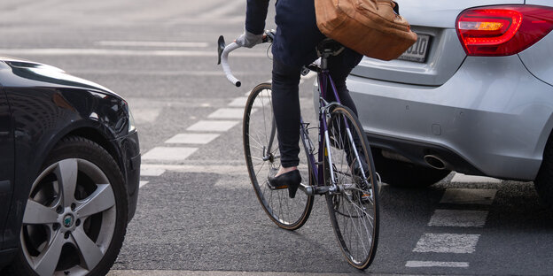 Eine Radfahrerin umfährt ein Auto, das auf einer Kreuzung auf dem Radweg steht