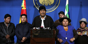 Evo Morales steht am Mikrofon begleitet von Anhängern