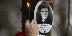 Gedenken mit einer brennenden Kerze an ein Opfer der Stalinschen Repressionen auf einem Friedhof in der Nähe von St. Petersburg
