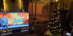 Weihnachtsbahm, Katstrophenbild im TV vor feuerrotem Himmel vor dem Fenster.