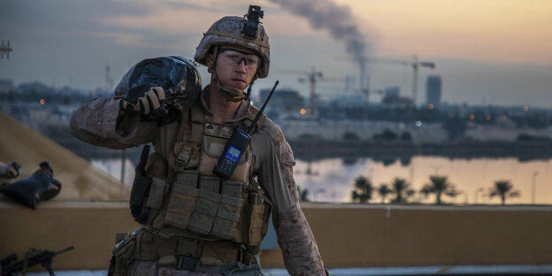 Ein US-Soldat in Bagdad trägt einen Sandsack auf der Schulter.