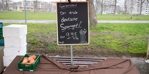 Eine Kiste mit Süßkartoffeln steht auf einem Wochenmarkt unter einem Schild mit der Aufschrift "Der erste deutsche Spargel". Um die Ausbreitung des Coronavirus zu verlangsamen hat Sachsen auch Wochenmärkte schließen lassen.
