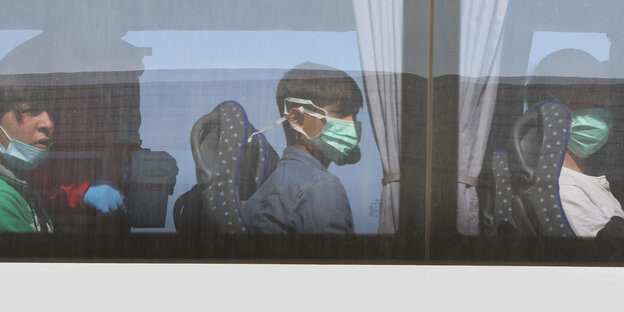 Kinder mit Schutzmasken sitzen im Bus