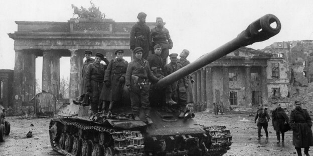 Soldaten der Roten Armee besteigen im Mai 1945 am Brandenburger Tor einen sowjetischen Panzer