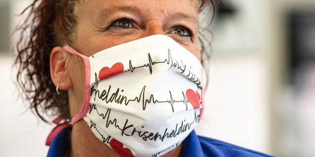 Frau trägt eine Maske mit der Aufschrift "Krisenheldin"