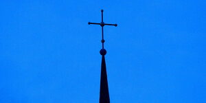 Das Kreuz einer evangelisch-lutherischen Kirche ist in der Abenddämmerung zu sehen