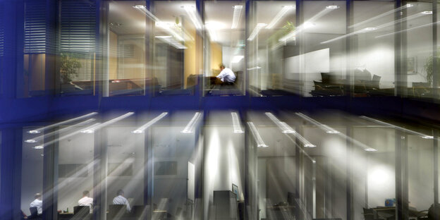 Nach Einbruch der Dunkelheit sitzt ein Angestellter in seinem Büro am Schreibtisch Nach Einbruch der Dunkelheit sitzt ein Angestellter in seinem Büro am Schreibtisch