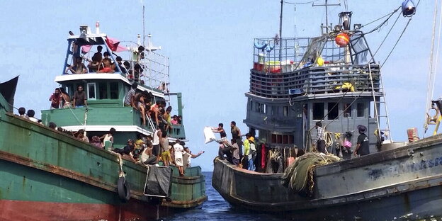 Ein Fischerboot und ein Boot mit Flüchtlingen Ein Fischerboot und ein Boot mit Flüchtlingen