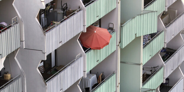 Orangefarbener Sonnenschirm auf einem Balkon eines Wohnhochhauses Orangefarbener Sonnenschirm auf einem Balkon eines Wohnhochhauses