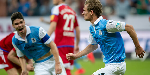 zwei Fußballspieler in weiß-blau jubeln, dahinter trotten zwei in rot davon. zwei Fußballspieler in weiß-blau jubeln, dahinter trotten zwei in rot davon.
