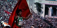 Läuferin mit marrokanischer Flagge in der Hand auf einer Ehrenrunde