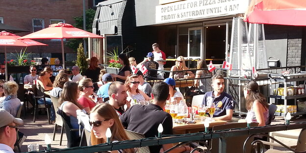 Fußballfans sitzen vor einer Pizzeria in Ottawa in der Sonne.