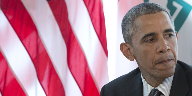 US-Präsident Obama sitzt erschöpft vor der US-Flagge US-Präsident Obama sitzt erschöpft vor der US-Flagge