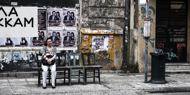 Eine Frau sitzt in Athen an einer improvisierten Bushaltestelle Eine Frau sitzt in Athen an einer improvisierten Bushaltestelle