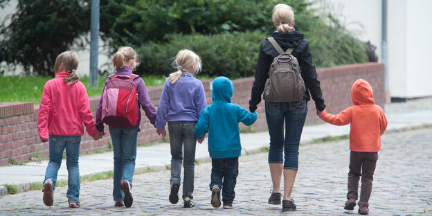 Eine Frau geht mit fünf Kindern über die Straße Eine Frau geht mit fünf Kindern über die Straße