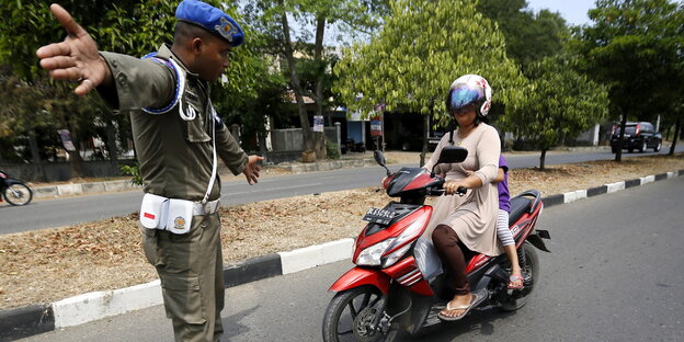 Eine Frau auf einem Roller und ein Polizist Eine Frau auf einem Roller und ein Polizist