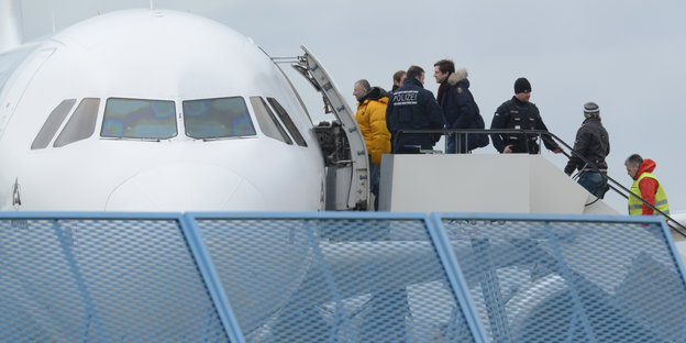 Abgelehnte Asylbewerber werden in ein Flugzeug geführt