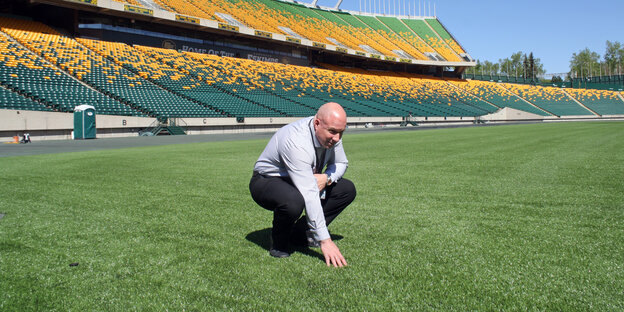 Kevin Koby, Chef des Commonwealth Stadium in Edmonton, streichelt den Kunstrasen in einem leeren Stadion Kevin Koby, Chef des Commonwealth Stadium in Edmonton, streichelt den Kunstrasen in einem leeren Stadion