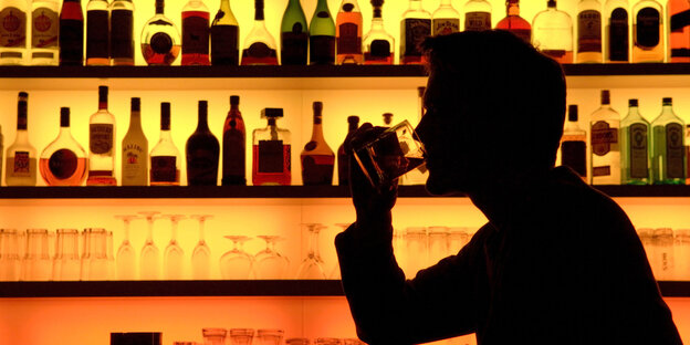 Ein Mann sitzt an einer Bar und trinkt Ein Mann sitzt an einer Bar und trinkt