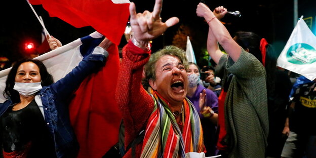 Demonstrierende schreien und heben ihre Arme während eines nächtlichen Protestmarsches die Höhe
