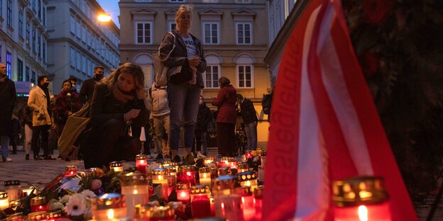 Zwei Frauen zünden an der Gedenkstätte für die Opfer des Terroranschlags in Wien Kerzen an