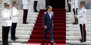 Ministerpräsident Tsipras kommt eine Treppe herunter, durch ein Spalier von Soldaten.