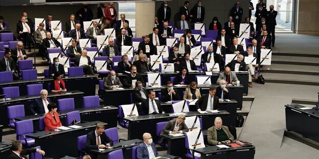 Die Fraktion der AfD im Bundestag. Sie sitzen auf ihren Stühlen und schauen böse. wegen Corona sind Plätze zwischen den Abgeordneten frei. Die haben sie mit Bändern geschmückt, als wären sie Teil einer Trauergemeinde.