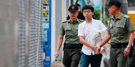 Joshua Wong, ein junger Mann in weißem Kurzarmhemd wird von zwei Polizisten geführt.