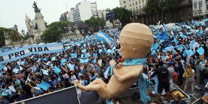 Viele Menschen mit blau-weißen Fahnen demonstrieren mit einem Plakat "Für das Leben" und einer großen Pappfigur eines Babys