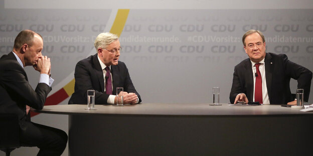 Friedrich Merz, Norbert Röttgen und Armin Laschet sitzen bei einer Fragerunde gemeinsam eán einem Tisch