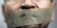 Der Mund eines Mannes ist mit Klebeband überklebt.