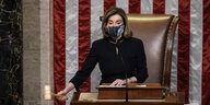 Nancy Pelosi mit einem Hammer in der Hand vor US-Flagge.