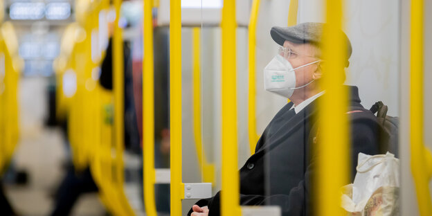 Ein Mann sitzt mit FFP2-Maske in der U-Bahn.