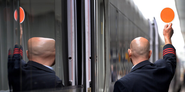Ein Schaffner hebt am am Hauptbahnhof Hannover seine Kelle und zeigt dem Lokführer „Grün“ an Ein Schaffner hebt am am Hauptbahnhof Hannover seine Kelle und zeigt dem Lokführer „Grün“ an