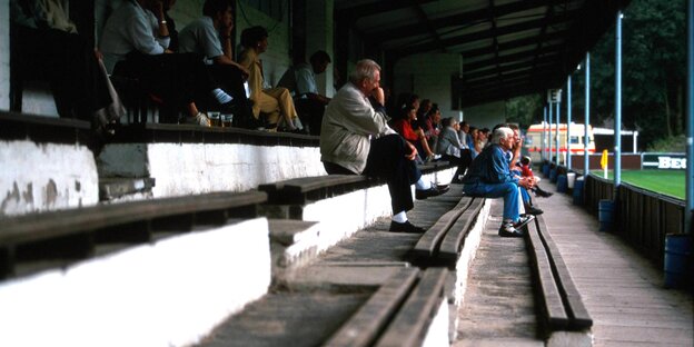 Fans sitzen auf einer baufälligen Tribüne Fans sitzen auf einer baufälligen Tribüne